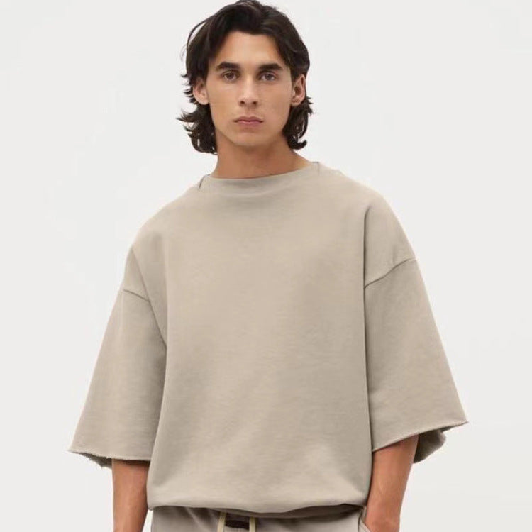 A man wearing a beige oversized fleece mid-sleeve sweatshirt.